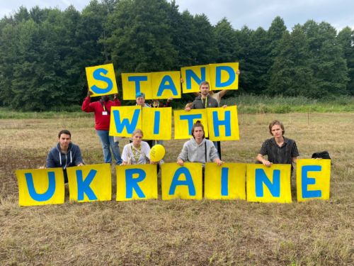 Eine Gruppe von Amnesty-Mitgliedern hält die Buchstaben "Stand with Ukraine" auf gelb-blauen Plakaten hoch.